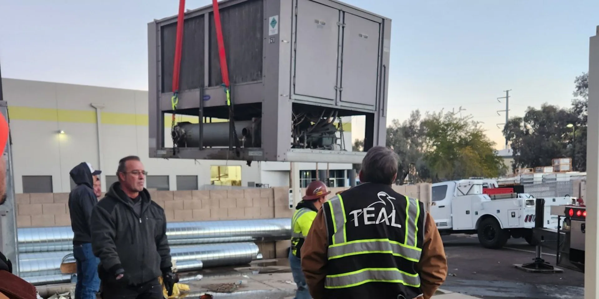 TEAL and Courier Graphics crews lifting a new air-cooled chiller into place at the Phoenix facility